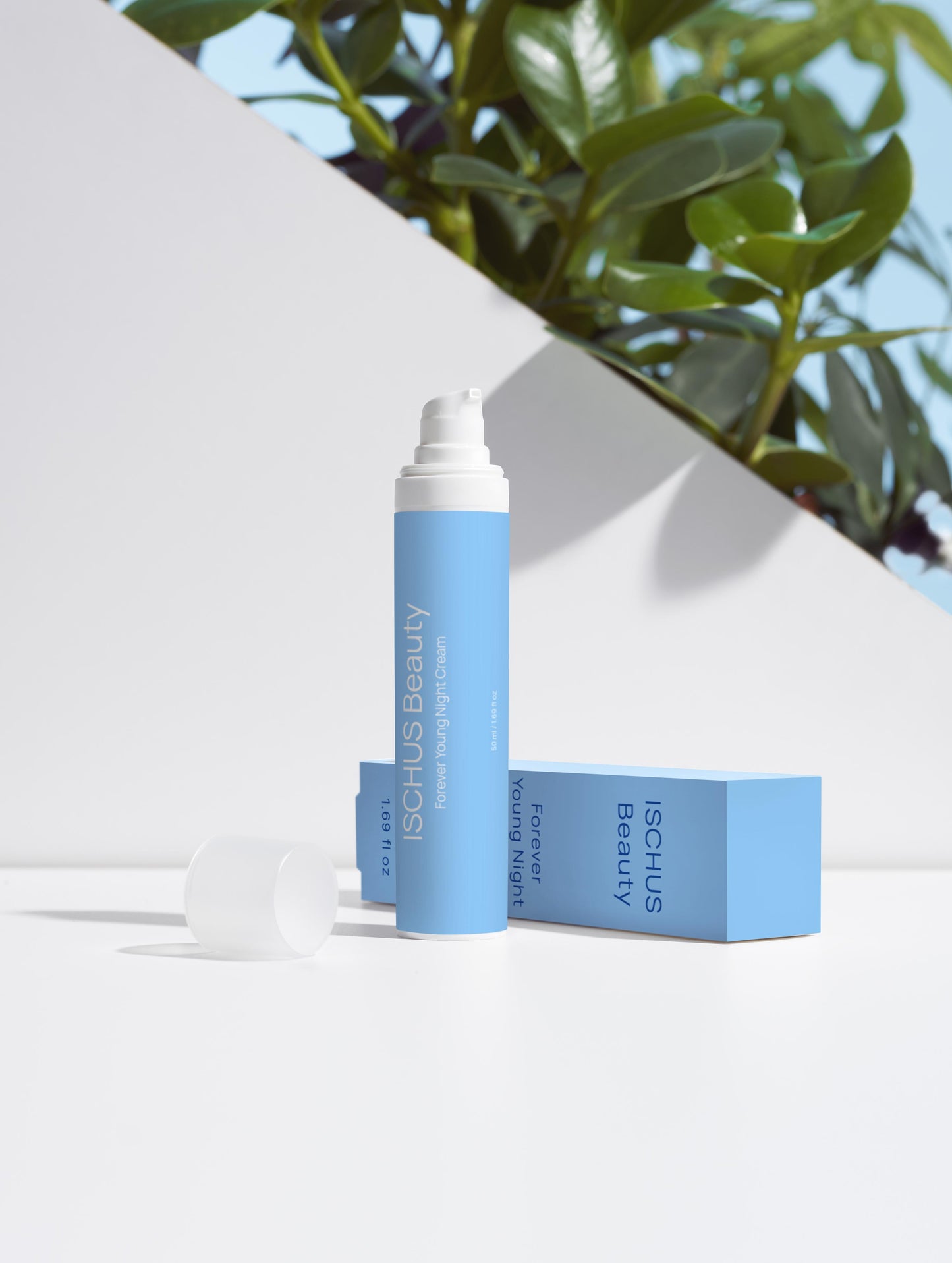A blue Forever Young Night Cream bottle with a pump and white cap sits next to its matching box on a white surface, with green plant leaves and a geometric white background.