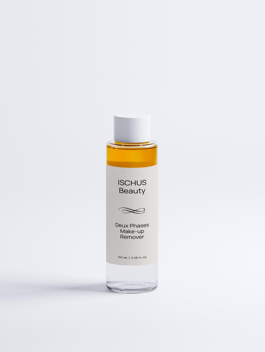A clear bottle of Deux Phases Make-up Remover with a white cap, showing separated yellow and clear layers, stands upright against a white background. Fragrance-free and suitable for all skin types.